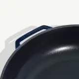 A close-up view of a cast iron skillet with a blue handle.