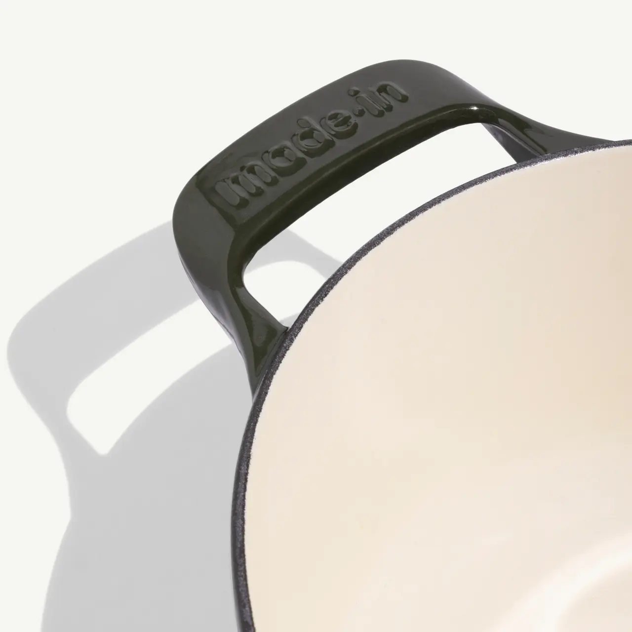 A black cooking pot with the words "made-in" embossed on its handle, showcasing a smooth, light-colored interior.