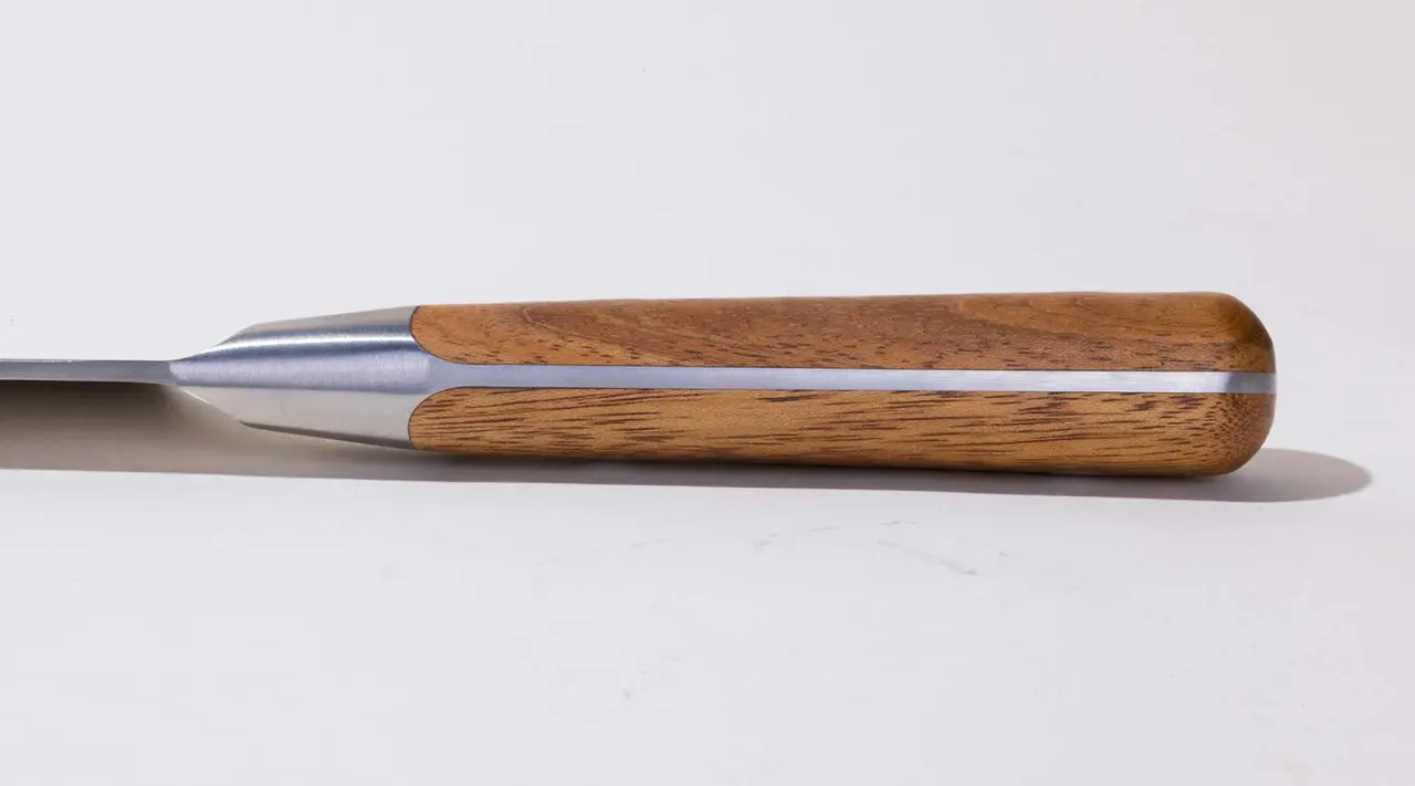 A close-up of a chisel with a wooden handle and a sharp metal blade on a white background.