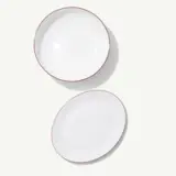Two white dishes with red rims are arranged on a plain background.