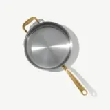 A stainless steel frying pan with a gold handle, featuring a reflective surface and a simple design.