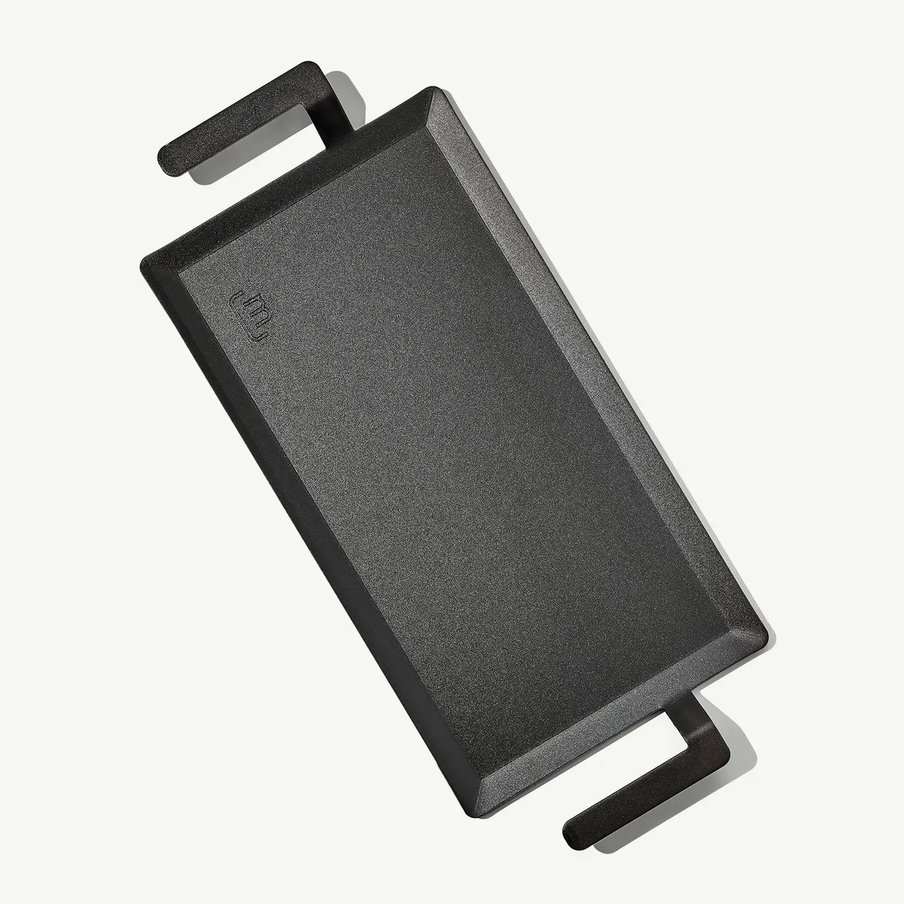 A rectangular black cast iron griddle with handles on both ends.