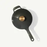 A dark green cooking pot with a brass knob and two handles is shown from a top-down perspective.
