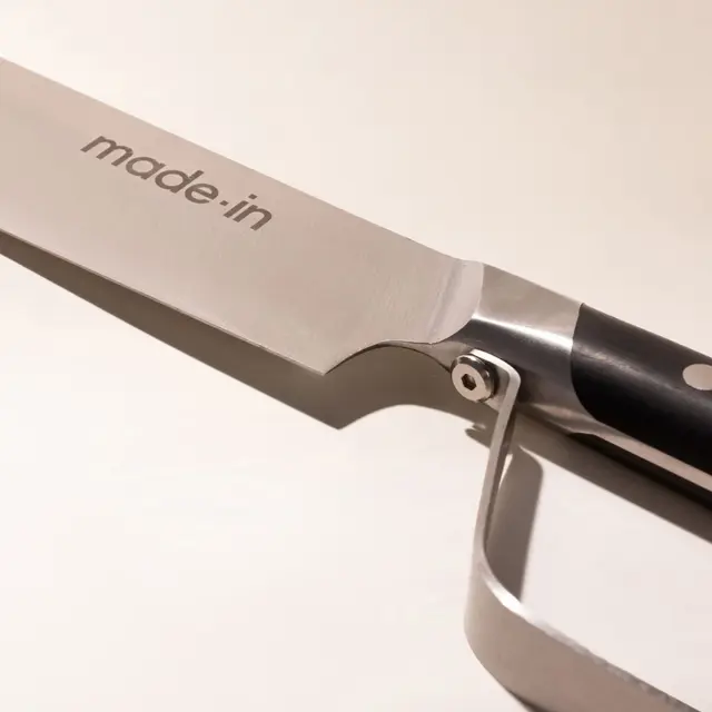 A close-up of a stainless steel knife blade with "made.in" engraved on it, highlighting the brand name against a plain background.