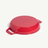 A round, bright red kitchen lid with two handles and embossed labeling on top.