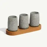 Three gray stone cups are placed on a wooden tray.