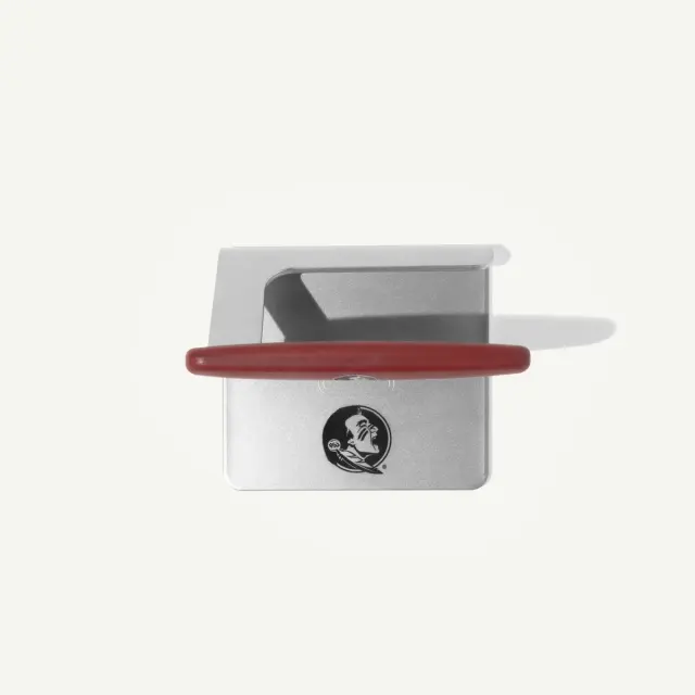 A metallic kitchen tool with a red handle, designed for slicing or serving, features a logo on its side.