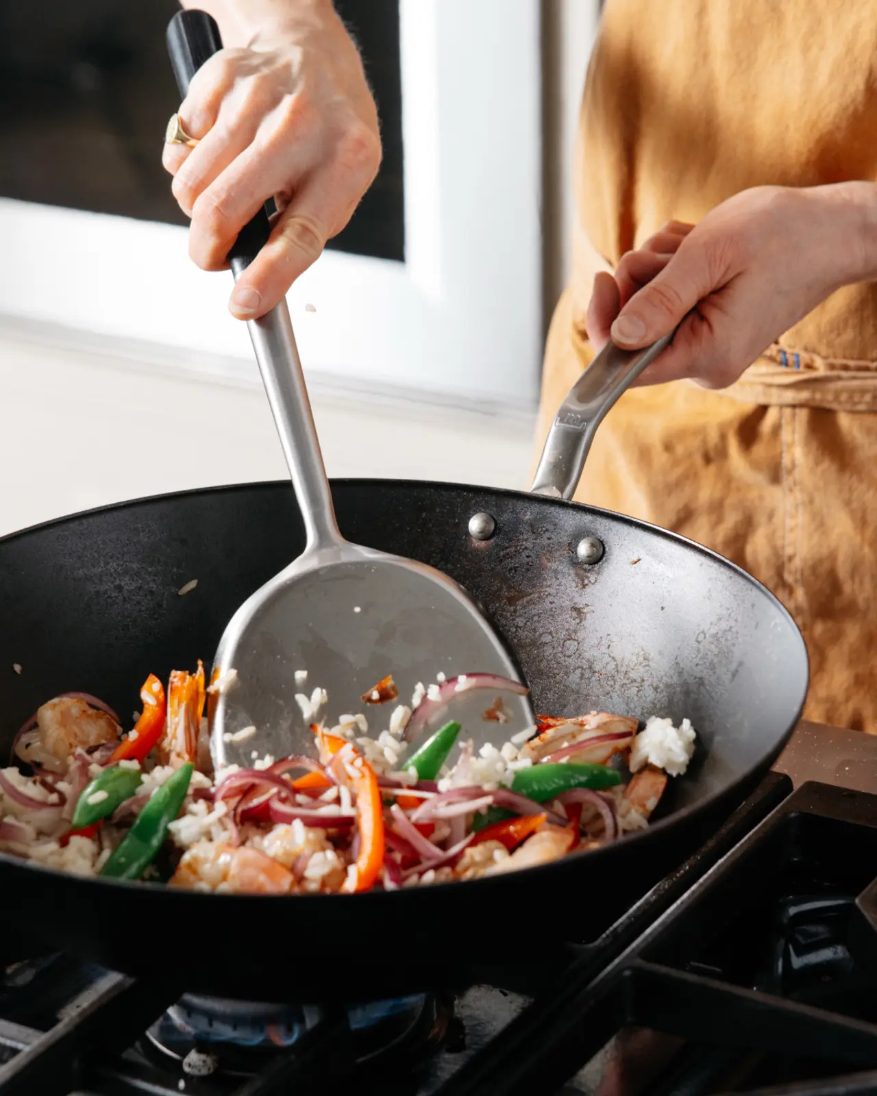 A chef stirs vegetables and rice in Made In’s Carbon Steel Wok over a gas flame.