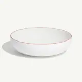 A white, round bowl with a thin red rim is shown against a plain background.