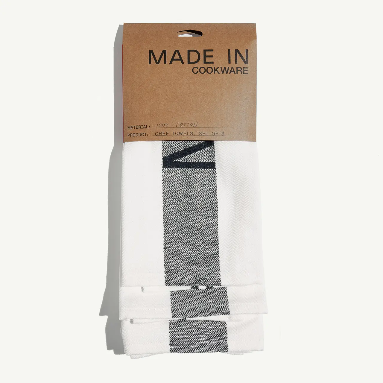 A pack of new, neatly folded white and gray kitchen towels is labeled by "MADE IN Cookware".