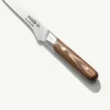 A kitchen knife with a wooden handle lies on a plain surface, casting a soft shadow to the side.