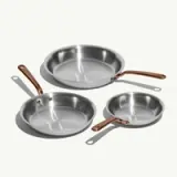 Three stainless steel frying pans of varying sizes, each with a sleek copper handle.