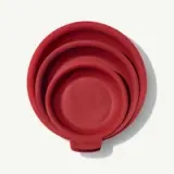 Four nested red measuring cups are stacked together.