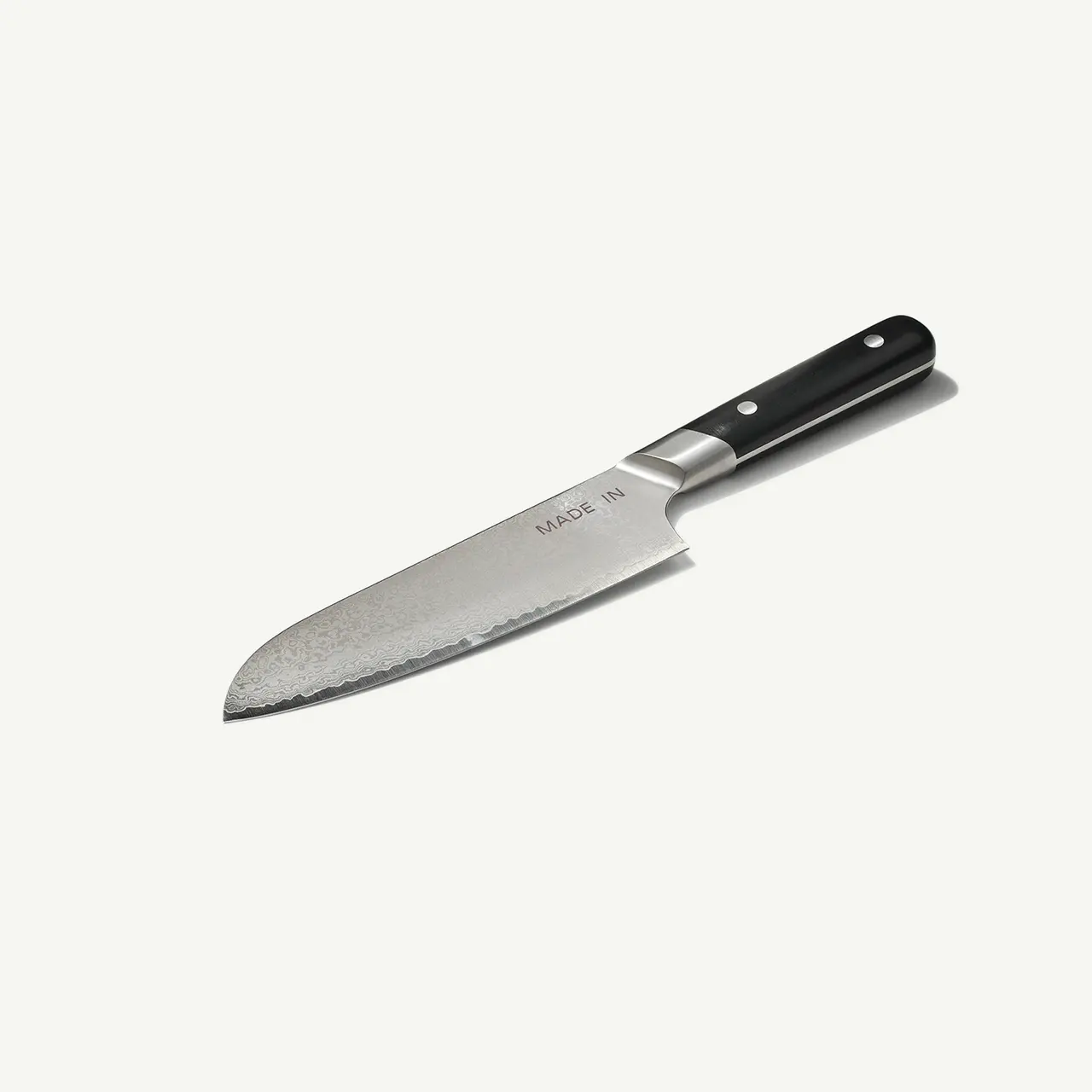 A chef's knife with a black handle and a stainless steel blade is displayed against a plain backdrop.