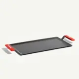 A black rectangular griddle with red handles on each side.