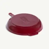 A deep red cast iron skillet with a smooth, flat bottom and a side handle.