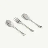 Three stainless steel utensils, including a serving spoon, serving fork, and soup spoon, are laid out on a plain background.