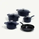 A set of five dark blue cookware including two pots with lids, one Dutch oven with lid, one sauté pan, and one frying pan.