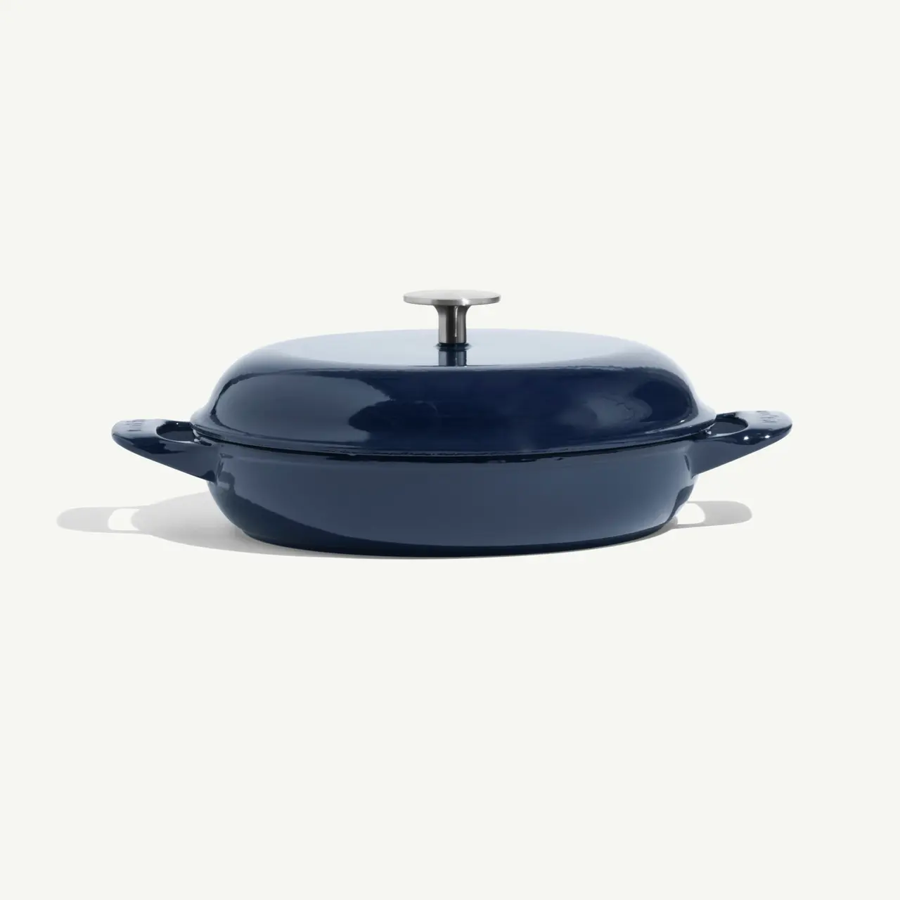 A navy blue, round cooking pot with a lid and handles is displayed against a light background.