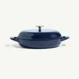 A navy blue, round cooking pot with a lid and handles is displayed against a light background.