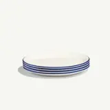 A stack of white plates with blue rims against a plain background.