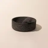 A stone molcajete, which is a traditional Mexican version of a mortar and pestle, on a neutral background.