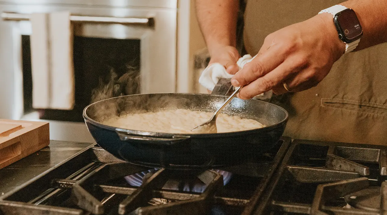 A person is cooking with a skillet on a gas stove.