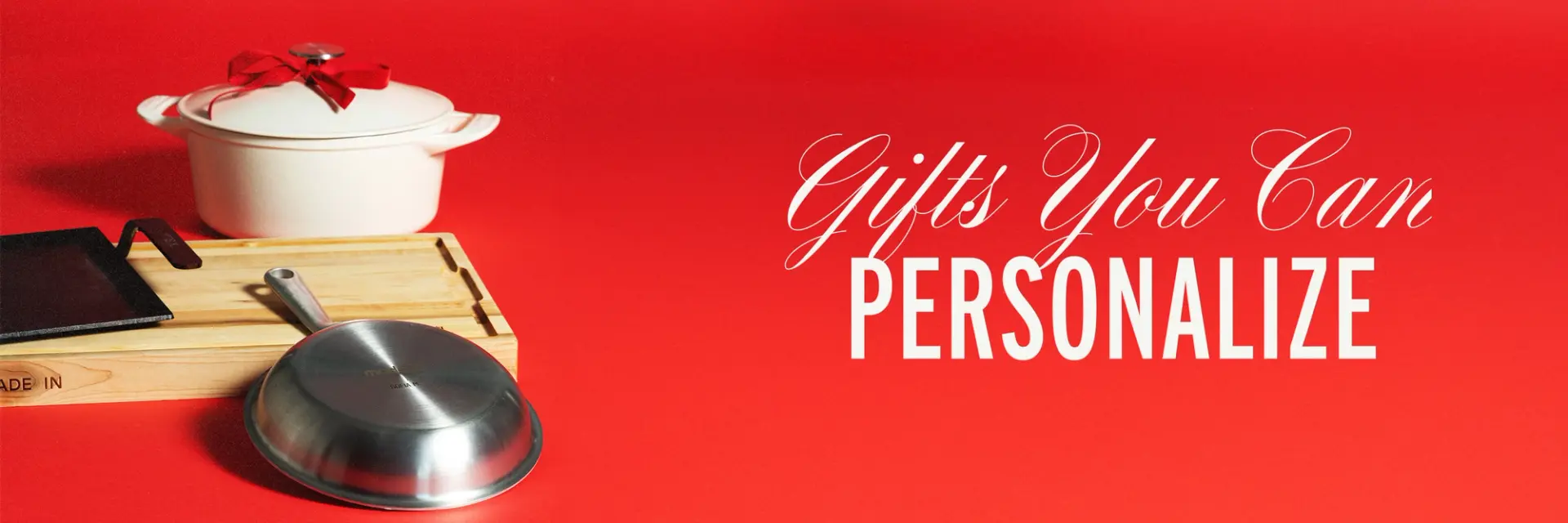 A white cooking pot, a wooden serving tray, and a stainless steel lid are displayed on a vibrant red background with the text "Gifts You Can PERSONALIZE."