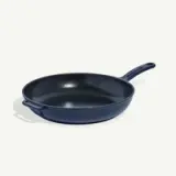 A navy blue cast iron skillet with a long handle rests on a white background.