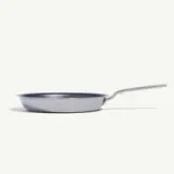 A silver frying pan with a long handle is positioned against a plain white background.