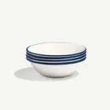 A stack of five white bowls with blue rims is placed against a plain background.