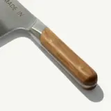 A stainless steel spatula with a wooden handle and brass rivets.