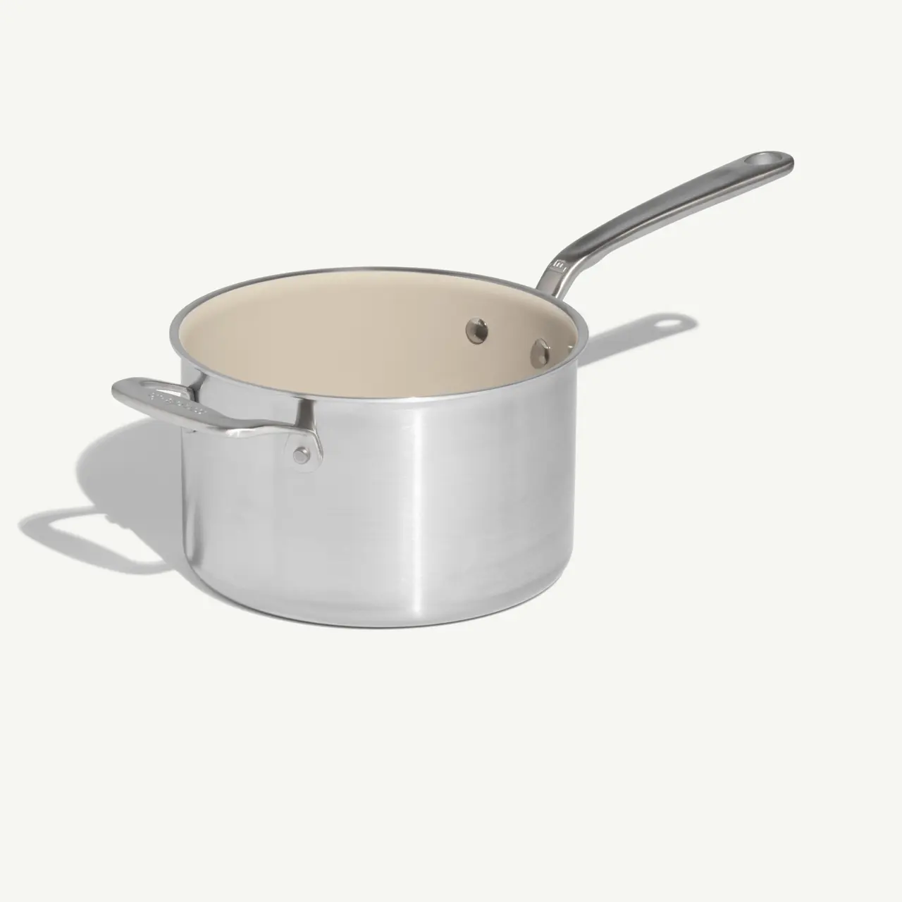 A stainless steel saucepan with a light-colored interior and a long handle.