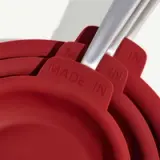 Stacked red frying pans with "MADE IN" embossed on the handles.
