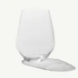 An empty glass is tipped over with liquid spilled on a flat surface.
