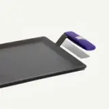 A rectangular metal griddle with a purple handle.
