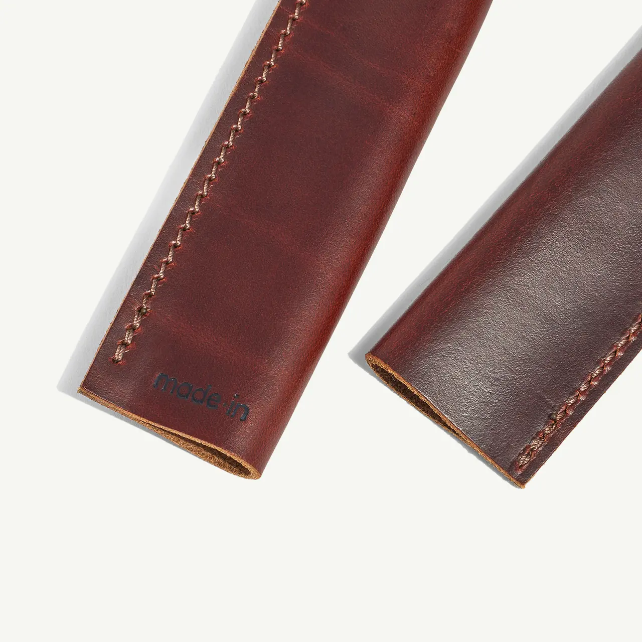 Two brown leather pen sleeves are displayed side by side with visible stitching details.