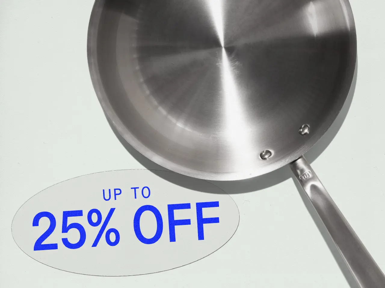 A stainless steel frying pan is displayed with a tag showing a discount of up to 25% off.