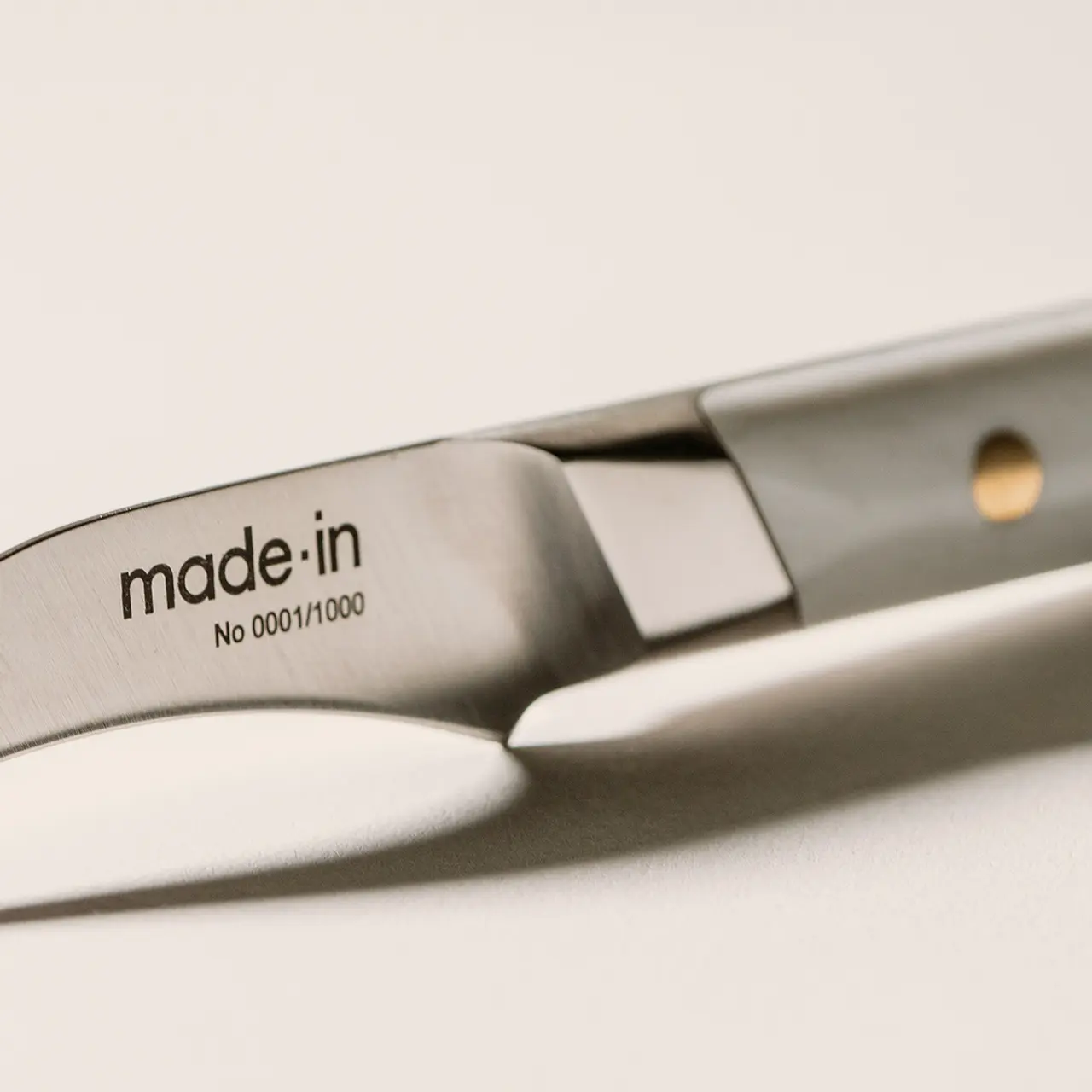 Close-up of a stainless steel knife with the text "made.in No 0001/1000" indicating it is the first in a limited series of production.