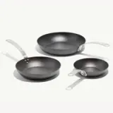 Three different-sized frying pans with metal handles are arranged on a white background.