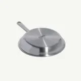 A stainless steel frying pan is shown lying upside down.