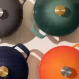 Four colorful pots with lids seen from above, each at a different angle, casting shadows on a light background.