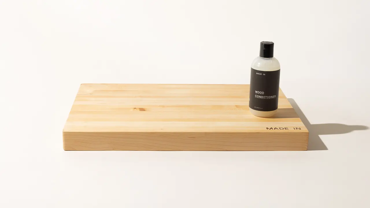 A bottle of skin conditioner sits atop a bamboo tray against a light background.