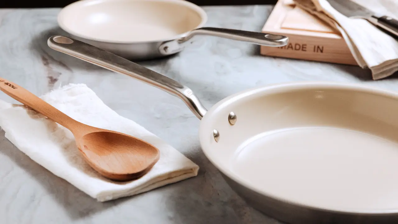 Two frying pans and a wooden spoon on a countertop suggest preparation for cooking.