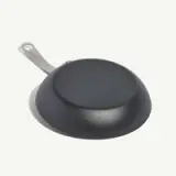 A black frying pan with a metal handle is shown upside down on a white background.