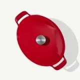 A red enameled cast iron Dutch oven with a metallic knob on its lid is shown from above.