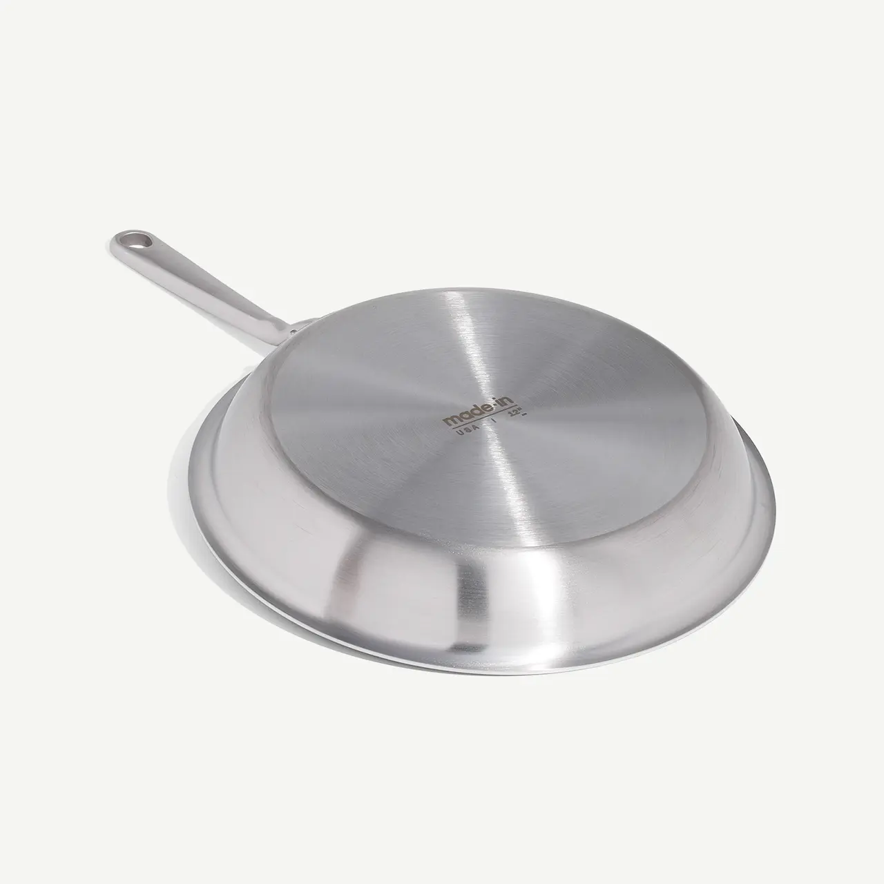 A stainless steel frying pan is displayed against a white background.