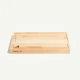 A rectangular wooden cutting board features a subtle engraved logo and the text "MADE IN."