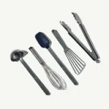 A set of five kitchen utensils, including a ladle, whisk, spatula, flat spatula, and tongs, is arranged on a clean background.