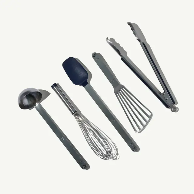 A set of five kitchen utensils, including a ladle, whisk, spatula, flat spatula, and tongs, is arranged on a clean background.